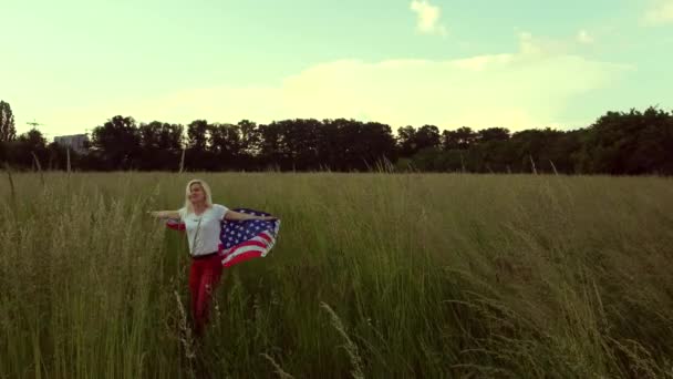 Mulher americana coberta com bandeira da América ao pôr-do-sol no campo de trigo — Vídeo de Stock