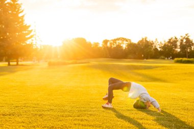 Küçük kız parkta jimnastik yapıyor.