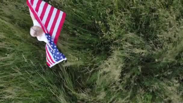 Американська жінка, покрита прапором Америки на заході сонця на пшеничному полі. — стокове відео