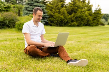 Parkta dizüstü bilgisayarıyla çalışan bir adam.