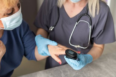 Doktor, yaşlı kadın hastayla hastalık belirtileri hakkında konuşmak, doktor yaşlı hastayla parmak ucu nabız oksimetresi, yaşlı sağlık kontrolü ve sağlık taraması, tıbbi teknoloji