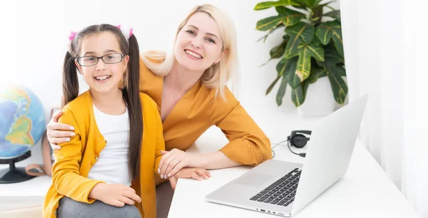 Sorridente giovane mamma caucasica e piccola figlia sedersi a casa utilizzare il computer portatile moderno insieme. Madre felice e bambina bambino studio online parlare in videochiamata sul computer. — Foto Stock