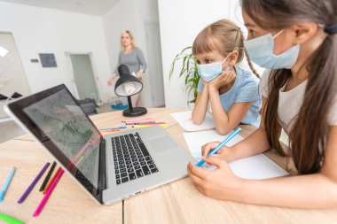 Evde çocuklu bir kadın internet öğretmenine yardım ediyor. Coronavirüs.