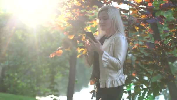 公園の屋外で携帯電話を使用して若い女性。テクノロジーライフスタイル。人々の仮想接続. — ストック動画