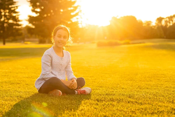 Caucasian little girl in the park in the rays of the setting sun — Stock Photo, Image