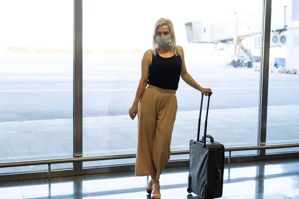 Egy nő maszkot visel, hogy megelőzze a vírust a poggyásszal a nemzetközi repülőtéren. Koronavírus elleni védelem — Stock Fotó