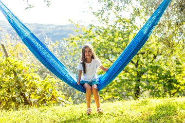 Yaz tatilindeki sevimli küçük kız hamakta dinleniyor.