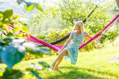 Mutlu genç kadın hamakta dinleniyor.