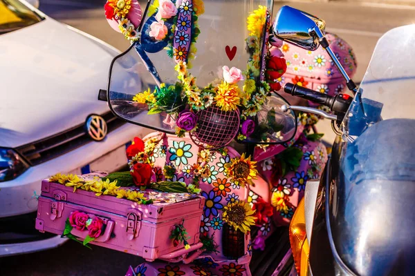 A scooter getting painted in violet flowers in the street — Stock Photo, Image