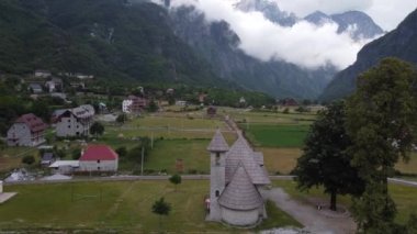 Arnavutluk 'un Theth kentinde rüzgarlı bir günde Alp dağlarının yamacında yeşil çimenli çayır