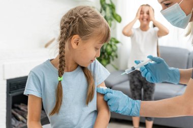 Hemşire küçük kız hastaya aşı yapıyor.