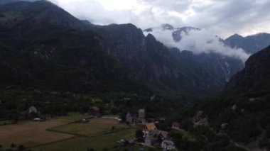Arnavutluk 'un Theth kentindeki Alpler' in tepesinde çayırları ve ormanları olan dev dağların kayalık yamacı