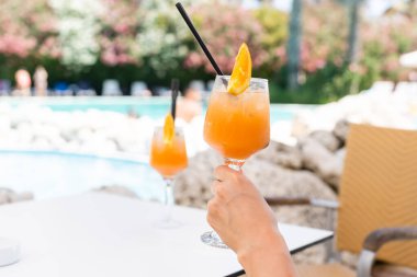 Parlak turuncu kokteyl havuzun kenarında duruyor.