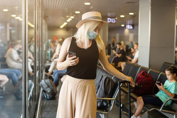 Voyageuse caucasienne avec masque médical à l'aéroport. Femme portant un masque protecteur contre le coronavirus. Masque hygiénique facial pour la sécurité extérieure. Sensibilisation environnementale ou propagation du virus peur. — Photo