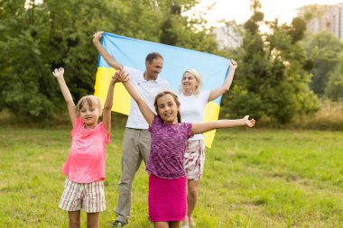 Tarlada Ukrayna bayrağı taşıyan mutlu aile.
