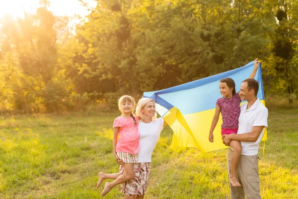 Flag Ukraine in hands of little girl in field. Child carries fluttering blue and yellow flag of Ukraine against background field. — Stock Photo, Image