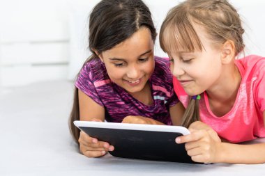 Küçük kızlar tablet bilgisayarı resim tahtası olarak kullanıyorlar. Birlikte resim yapıyorlar.