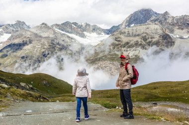 Sırt çantalı anne ve kızı gün içinde dağların yamacında oturuyorlardı..