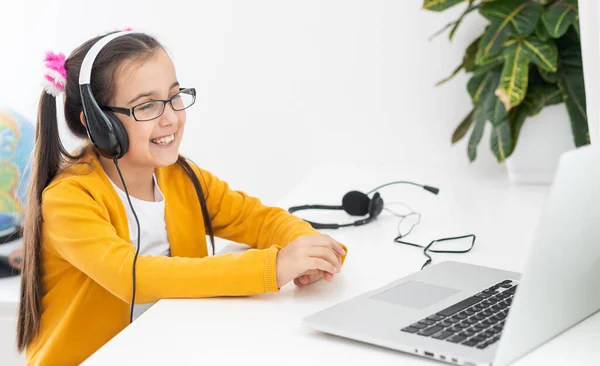 Closeup foto de pouco bonito aluno escola senhora falar skype notebook online aula vídeo chamada sit desk uso fones de ouvido distância cumprimentar colegas de classe onda braço quarentena estudo sala de estar dentro de casa. — Fotografia de Stock