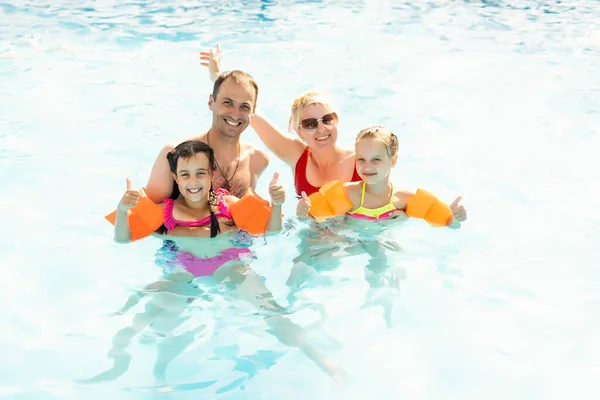 Familia feliz en la piscina, divirtiéndose en el agua, madre con niños disfrutando del parque acuático, resort de playa, vacaciones de verano, concepto de vacaciones — Foto de Stock