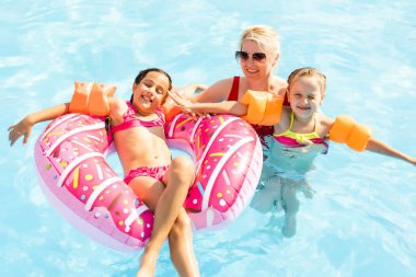 Denizde tropik bir tatil köyünde mavi yüzme havuzunda oynayan mutlu bir aile. Yaz tatilleri konsepti.
