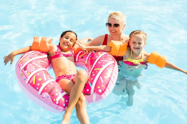 Familia feliz jugando en el agua azul de la piscina en un complejo tropical en el mar. Concepto vacaciones de verano. — Foto de Stock