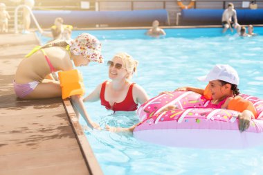 Mutlu aile yaz tatilinde eğleniyor, yüzme havuzunda oynuyor. Etkin sağlıklı yaşam tarzı konsepti