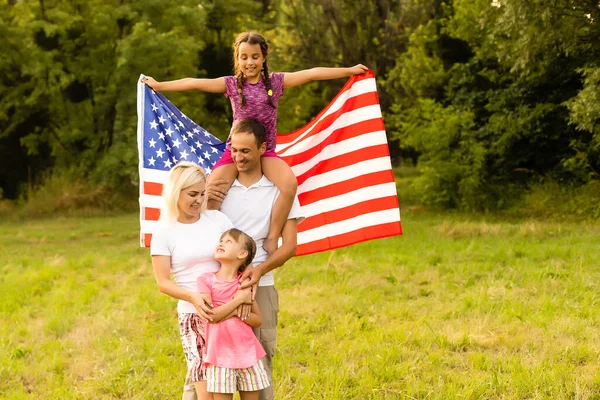 Happy family with the American flag in a wheat field at sunset. Independence Day, 4th of July. — Stock Photo, Image