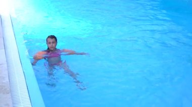 Güzel küçük kız havuzda yüzüyor ve eğleniyor.