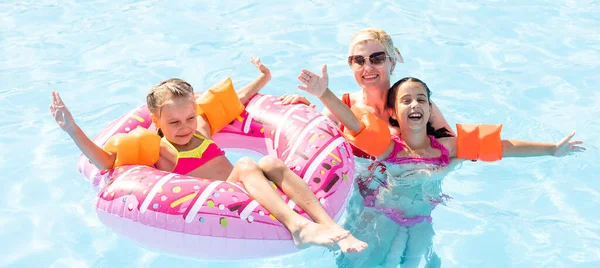 Familia feliz en la piscina, divirtiéndose en el agua, madre con niños disfrutando del parque acuático, resort de playa, vacaciones de verano, concepto de vacaciones — Foto de Stock