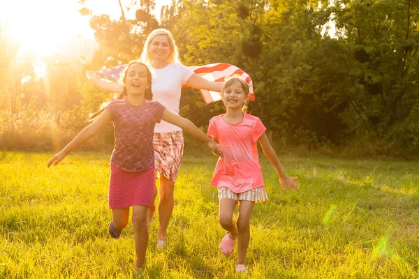 해 가 지는 야외에서 미국 국기를 들고 행복 한 가족 — 스톡 사진