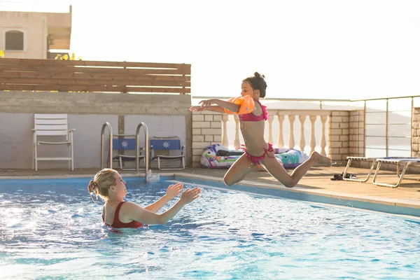 Güzel bir kadın küçük kızı havuza atlarken yakalar. — Stok fotoğraf