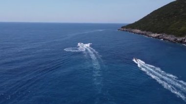 Mavi berrak sularda bir teknenin drone görüntüsü. Mavi denize giden beyaz bir teknenin üst görüntüsü. Büyük sürat teknesi yüksek hızda hareket ediyor. Seyahat - resim