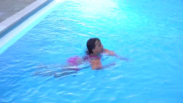 Pretty little girl swimming in outdoor pool and have a fun with inflatable armbands — Stock Video