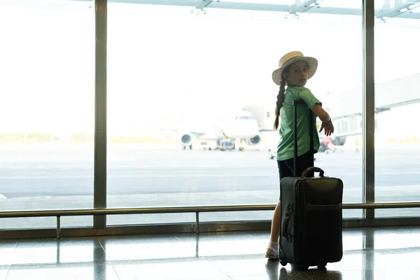 Concept de tourisme, vacances, enfance et transport - petite fille souriante avec sac de voyage, billet et passeport sur fond d'aéroport. — Photo