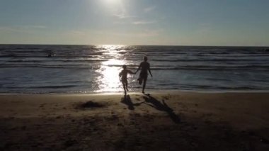 Anne ve kızı kumlu sahilde oynuyorlar. Kumlu sahilde mutlu bir aile