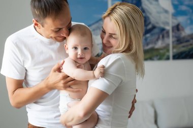 Evde bebekle mutlu genç ebeveynlerin portresi.