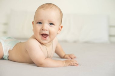 Beyaz güneşli yatak odasında sevimli bir erkek bebek. Yeni doğmuş çocuk yatakta dinleniyor. Küçük çocuklar için çocuk odası. Aile sabahı evde. Yeni doğan çocuk