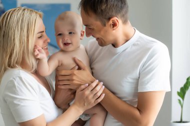 Evde bebekle mutlu genç ebeveynlerin portresi.