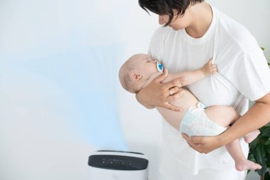 Anne ve bebek evde hava temizleyicinin yanında.