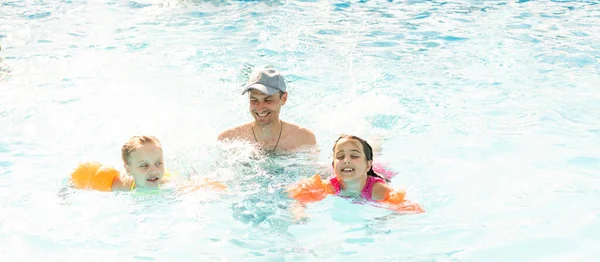 Familia feliz divirtiéndose en las vacaciones de verano, jugando en la piscina. Concepto de estilo de vida saludable activo — Foto de Stock