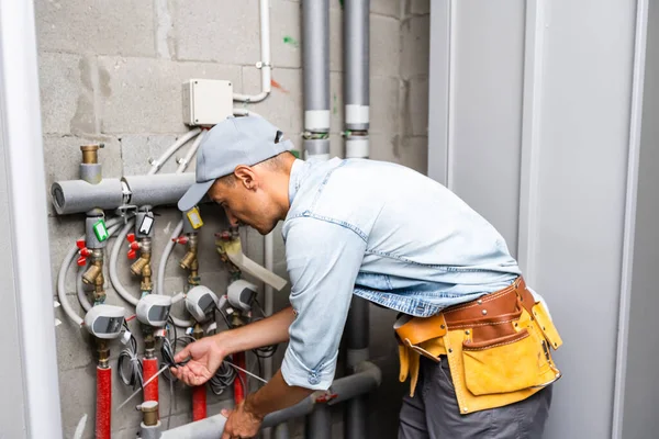 Encanador masculino verifica tubos para abastecimento central de água quente e fria do apartamento — Fotografia de Stock