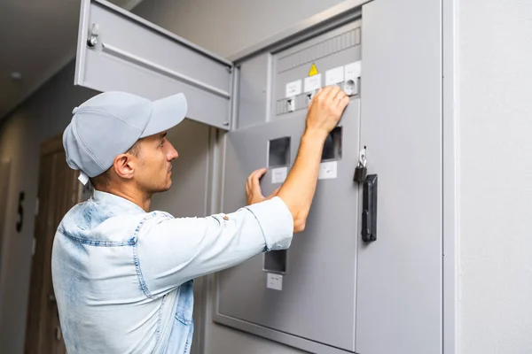 Jeune électricien souriant faisant son travail, panneau électrique — Photo