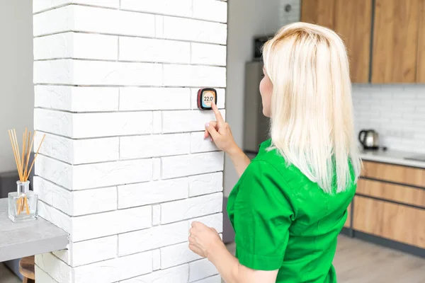 Nahaufnahme einer Frau, die die an der Wand montierte digitale Thermostat-Steuerung für die Zentralheizung zu Hause anpasst — Stockfoto