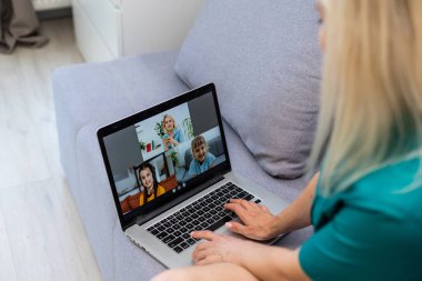 Evde video konferansı için dizüstü bilgisayar kullanan genç bir kadının kırpılmış görüntüsü