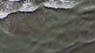 Güzel bir manzara, denizin kumlu sahilinde bir dalga akıyor, yakın plan.