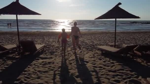 Anne ve kızı sahilde yürüyor. — Stok video