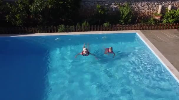 La madre con su hijita se divierte en la piscina. Mamá juega con el niño. La familia disfruta de vacaciones de verano en una piscina. — Vídeos de Stock