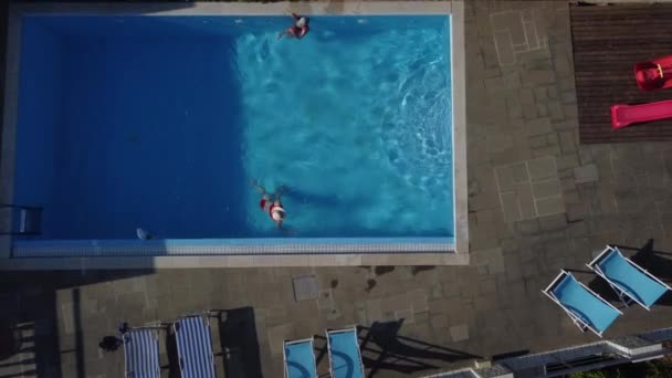 The mother with little daughter have fun in the pool. Mom plays with the child. The family enjoy summer vacation in a swimming pool. — Stock Video