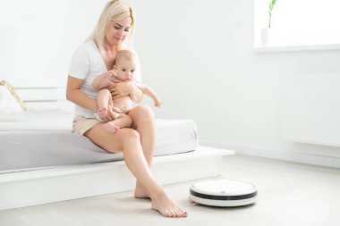 Küçük bebek evdeki robot elektrik süpürgesine bakıyor..